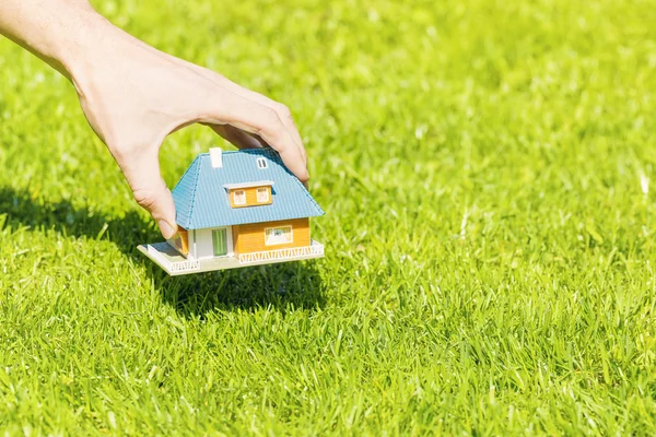 Nya hem concept, hand sätta huset skalenlig modell på gräs — Stockfoto