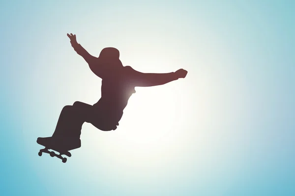 Скейтборд - силуэт фигуриста против голубого неба на закате — стоковое фото