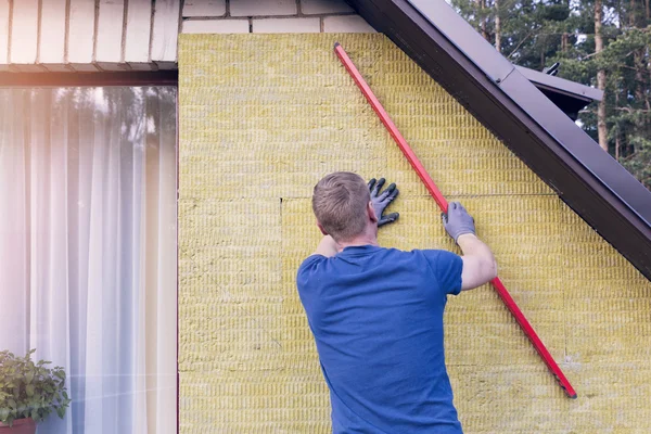 Trabajador de la construcción comprueba el nivel de la pared de la casa aislada — Foto de Stock