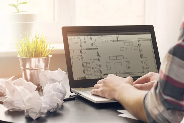 Arquiteto, designer de interiores trabalhando no laptop com planos de chão — Fotografia de Stock