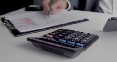 muhasebeci hesap makinesi dijital tablet ve grafikleri kullanarak ofiste rapor üzerinde çalışıyor