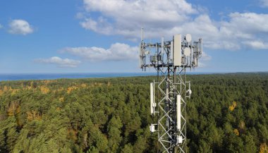Telekomünikasyon kulesi. Orman ve mavi gökyüzü arka planında 5G ağları için antenleri var. mobil internet yayını