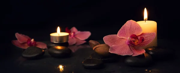 温泉和替代疗法 有按摩石和兰花的蜡烛 背景是黑色的 — 图库照片
