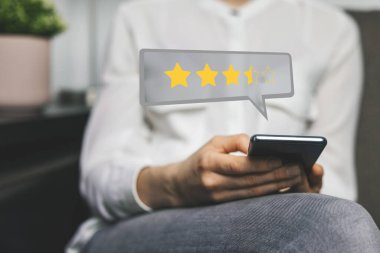 Müşteri İncelemesi - telefon kullanan kadın geri bildirim yapmak ve yıldızlarla ilgili deneyimlerini değerlendirmek için servis kalitesi veya ürün kalitesi