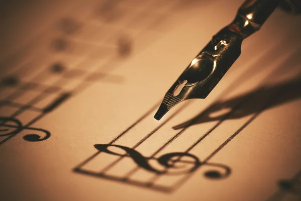 stock image writing musical notes on sheet with quill pen and ink. music education. closeup