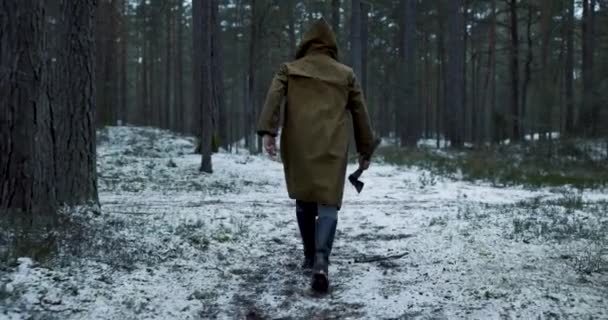 穿着褐色帽带斧头的疯子在森林里追杀受害者 — 图库视频影像
