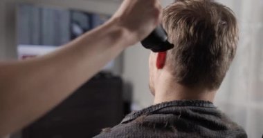 Karısı evde buz hokeyi izlerken kocasının saçını makasıyla kesiyor.