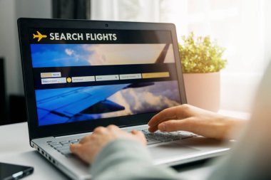Online rezervasyon - uçuş araması ve rezervasyon için dizüstü bilgisayarda internet sitesi kullanan kişi