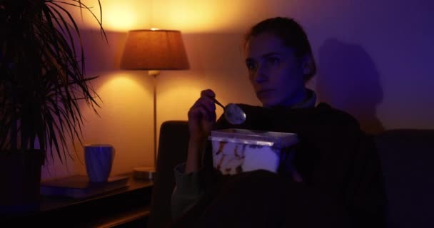 Samotna Kobieta Jedząca Lody Siedząc Kanapie Oglądając Telewizję Domu — Wideo stockowe