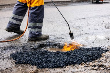 İşçiler yoldaki çukurları bitumen asfalt ile onarıyor