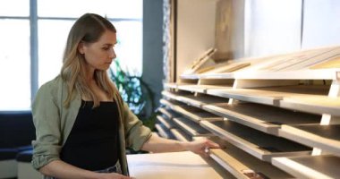 İç tasarım mağazasındaki yeni evi için numunelerden malzeme seçen genç bir kadın.