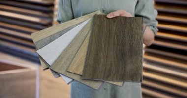 Elinde vinil döşeme örnekleri olan bir mağaza satıcısı.