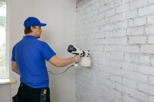 Человек Рисует Стены Старого Кирпича Белый Цвет Распылителем Краски — стоковое фото