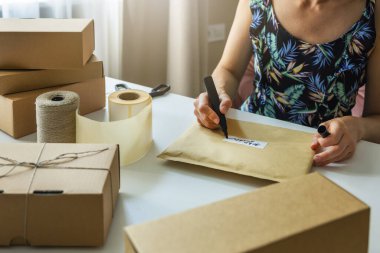 Sevkiyat için eve zarf gönderme etiketi yazan küçük bir dükkan sahibi.