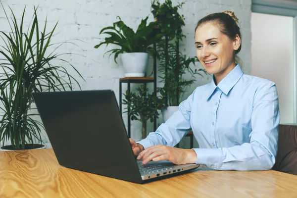 Uśmiechnięta Kobieta Pracująca Laptopie Jasnym Nowoczesnym Biurze Zielonymi Roślinami — Zdjęcie stockowe