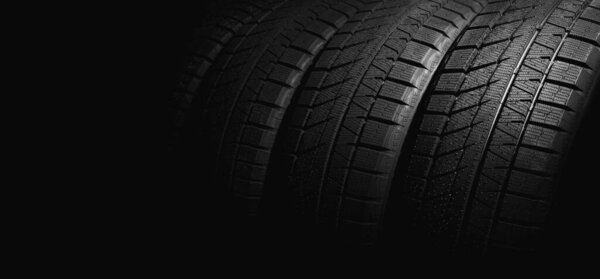 new winter car tires on black background. copy space
