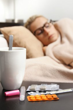sick woman sleeping in bed, focus on pills clipart