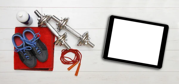 Equipo de fitness y tableta digital en blanco en el piso del gimnasio — Foto de Stock