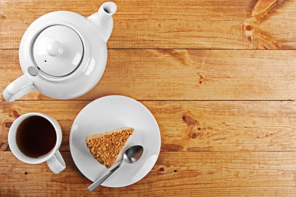 Pedaço de bolo e panela de chá na mesa de madeira — Fotografia de Stock