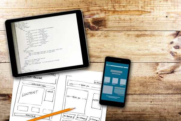 Website wireframe sketch and programming code on digital tablet — Stock Photo, Image