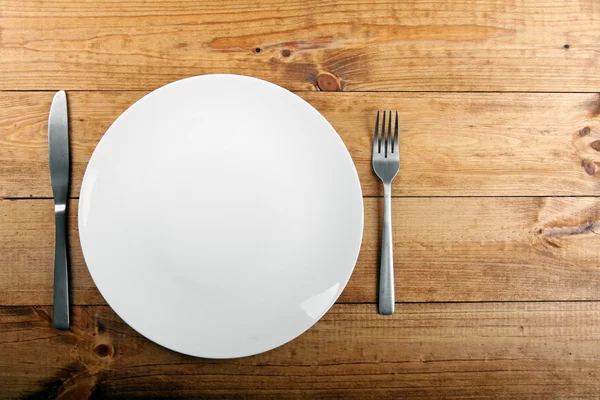 Empty white plate on brown wooden table — Stock Photo, Image