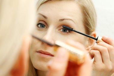 kadın aynanın önünde maskara uygulamak