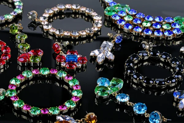 Bijoux de luxe en pierres précieuses sur table noire brillante — Photo