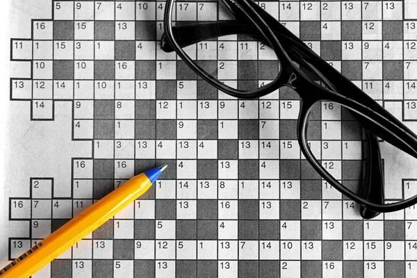 Top view of blank crossword puzzle with black eyeglasses and a p — Stock Photo, Image