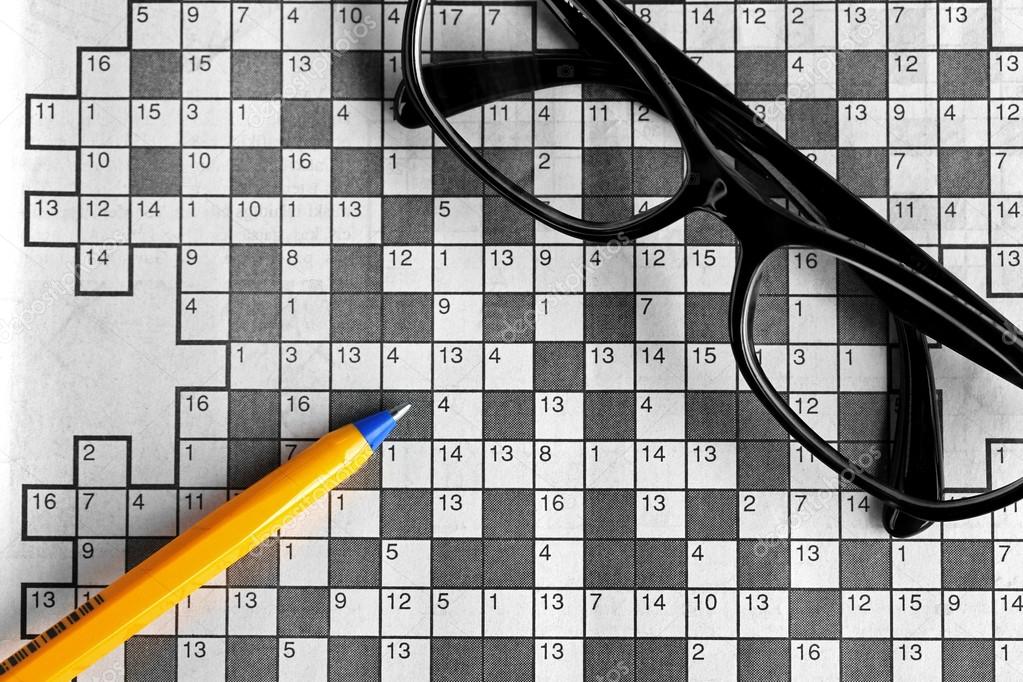 top view of blank crossword puzzle with black eyeglasses and a p