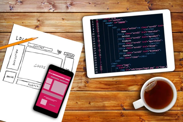 Web site wireframe sketch and programming code on digital tablet — стоковое фото