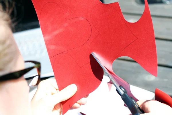 Cutting heart shape out of red paper — Stockfoto