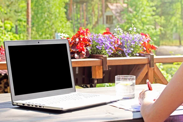 Arbeit von zu Hause aus, Tisch mit Laptop auf der Terrasse lizenzfreie Stockfotos