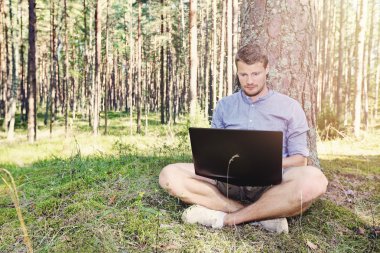 genç adam açık havada doğa içinde onun laptop ile çalışma