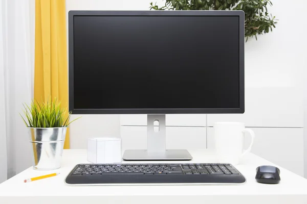 Blank monitor on table in bright interior — Stock Photo, Image