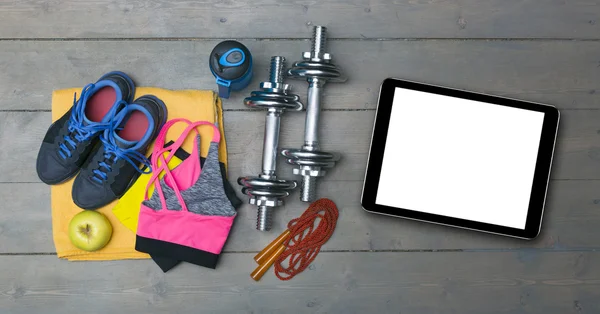 Красочное фитнес-оборудование и чистый цифровой планшет на полу спортзала — стоковое фото