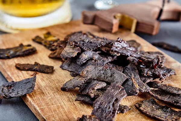 Carne seca sobre tabla de madera y cerveza — Foto de Stock