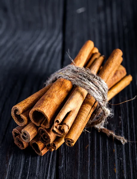 Cinnamon sticks on black wood board — Stock Photo, Image