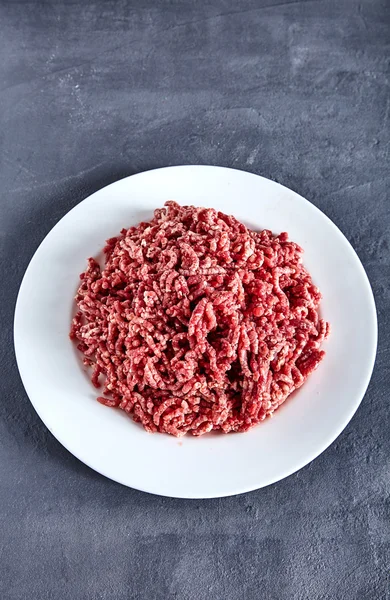 Carne molida cruda en un plato blanco —  Fotos de Stock