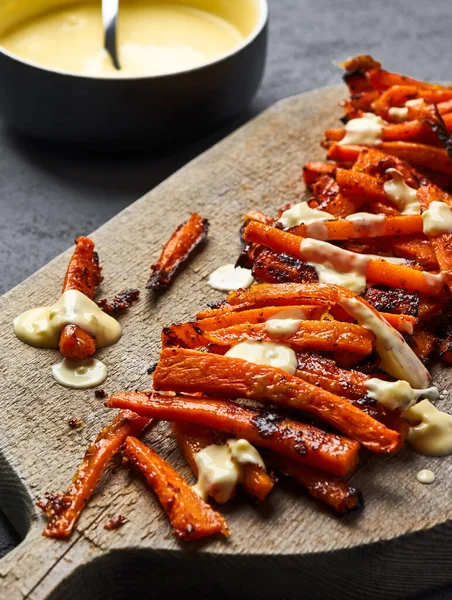 As cenouras caramelizadas fatiadas com parmesão estão em uma tábua de corte. 45 ângulo de visão — Fotografia de Stock