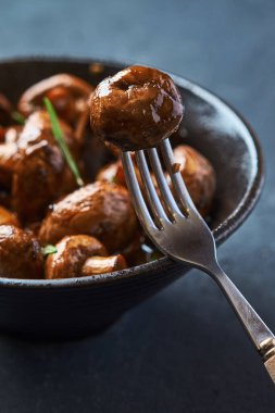 Teriyaki soslu fırın mantarı. Tabağın yanındaki çatala saplanmış bir mantar.