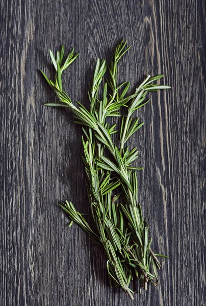 Bunch of rosemary on dark wood — Stock Photo, Image