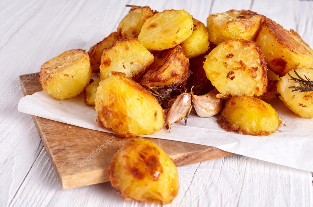 Roast potatoes seasoned with salt on wood background
