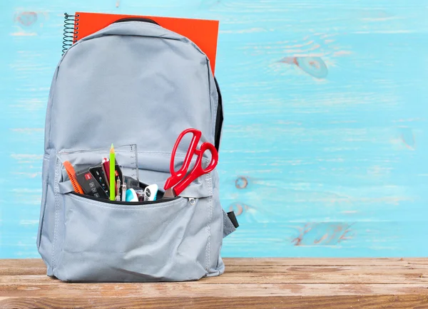 Okul araçları ile turkuaz arka plan üzerinde sırt çantası — Stok fotoğraf