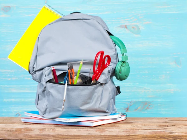 Mochila con herramientas escolares sobre fondo turquesa — Foto de Stock