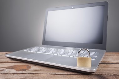 Gri arka plan üzerinde asma kilit ile dizüstü bilgisayar