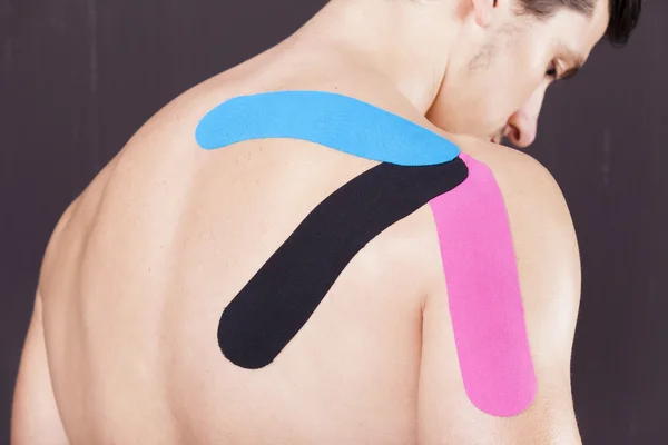 与 kinesiotaping 的肩膀的肌肉男 — 图库照片