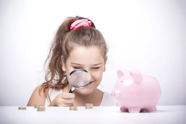 Girl with a magnifying glass and looking to the savings — Stock Photo, Image
