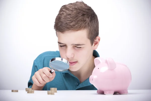 Menino com lupa olhando para suas economias — Fotografia de Stock