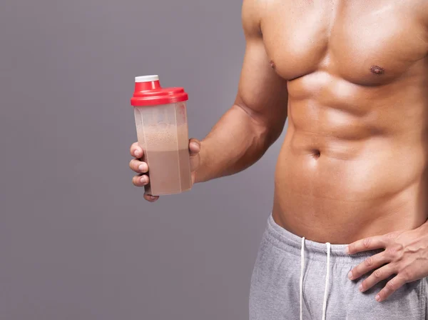 Gespierde man die een shaker met chocolade eiwit — Stockfoto