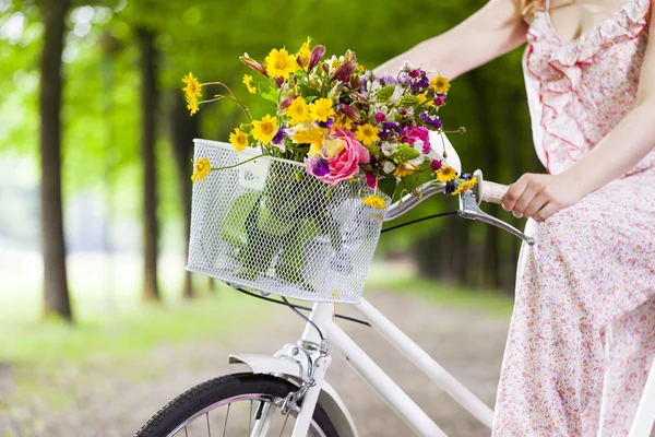 Женщина держит винтажный велосипед с цветами — стоковое фото